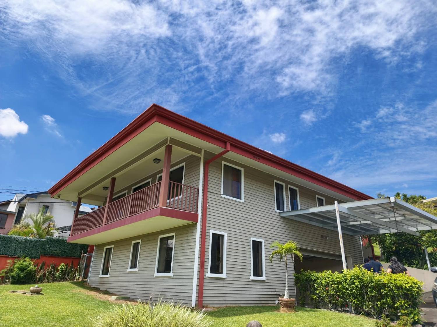 Front of the two-story home with a covered balcony and landscaped garden